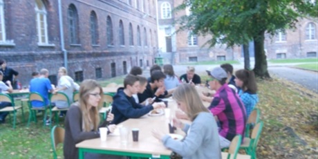 Powiększ grafikę: Wychowankowie jedzą przy stołach ustawionych na zewnątrz budynku przy ul. Podwale Staromiejskie.