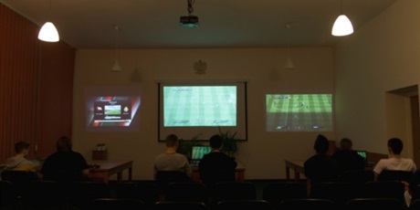 Powiększ grafikę: W półmroku jednocześnie rozgrywają się trzy meczę w Fifę. Rozgrywki można obserwować na ścianach dzięki podłączonych rzutnikom. 
