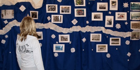 Powiększ grafikę: Wychowanka podziwia fotografie przywieszone na niebieskim materiale.