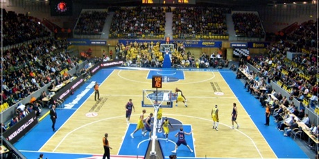 Powiększ grafikę: Rozgrywający się mecz koszykówki. Zdjęcie wykonano wysoko z widowni.