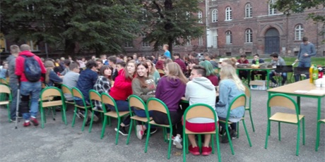 Powiększ grafikę: Wychowankowie siedzą przy stołach, na tyłach budynku przy ul. Podwale Staromiejskie.